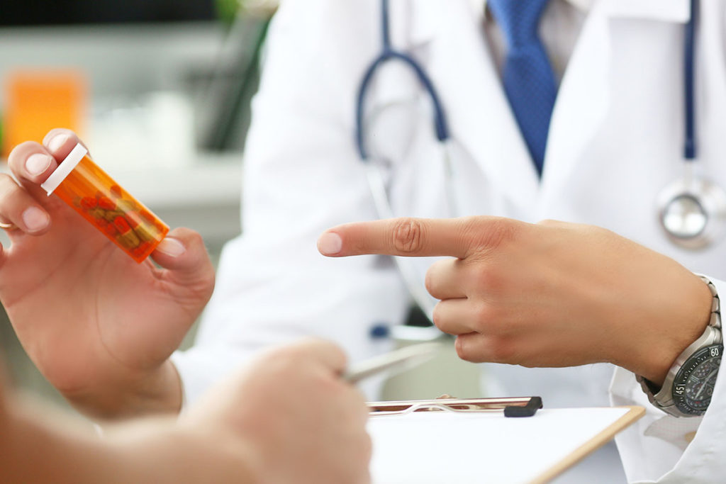 a healthcare worker points at a bottle of pills possibly warning someone of commonly abused prescription drugs