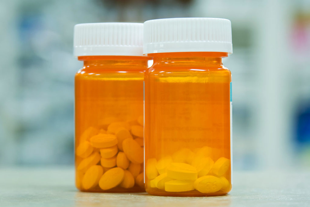 two pill bottles sit beside each other it is hard to tell by sight the difference in opiates vs opioids