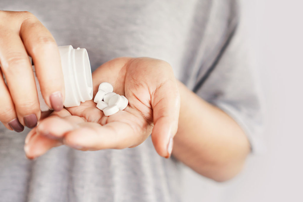 a person pours multiple pills into their hand possibly a sign of painkiller abuse