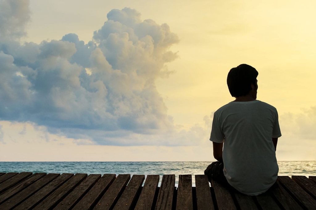 a person sits on a fence thinking about medical detox for drug addiction